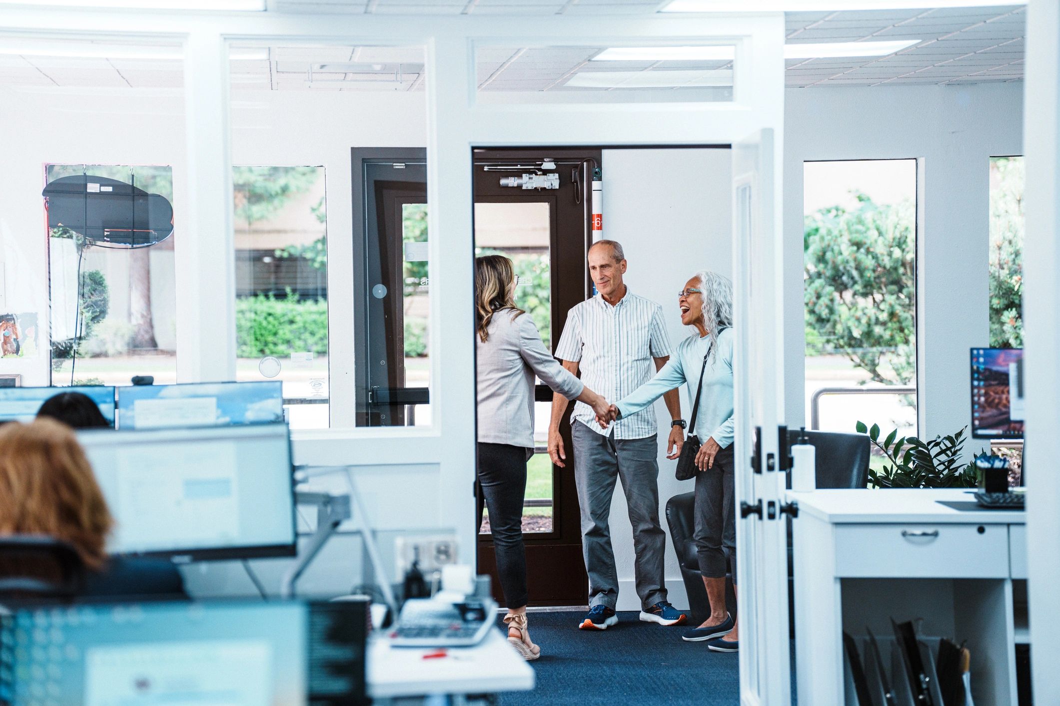 Bank employee greeting senior clients with handshake during financial consultation